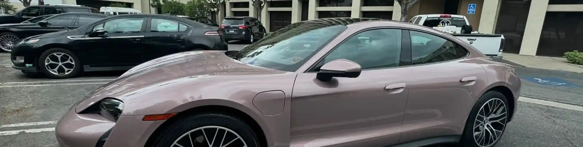 A pink Porsche in front of a building receives luxury vehicle mobile detailing from Armando King Mobile Detailing.