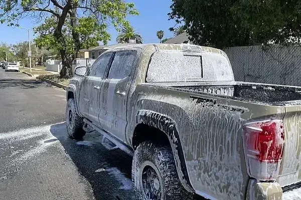 A snow covered car on the street is handled by Armando King Mobile Detailing using mobile car detailing.