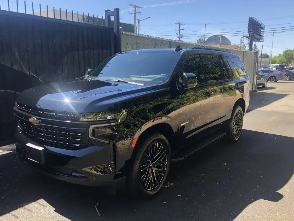 A black SUV at a commercial building receives mobile car detailing from Armando King Mobile Detailing.