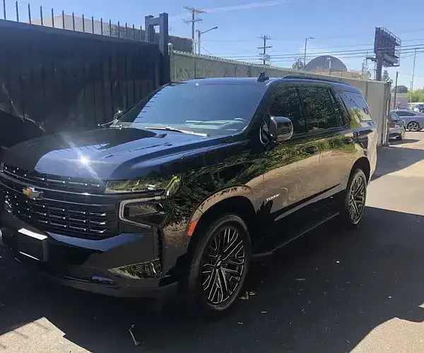 A black SUV at a commercial building receives mobile car detailing from Armando King Mobile Detailing.