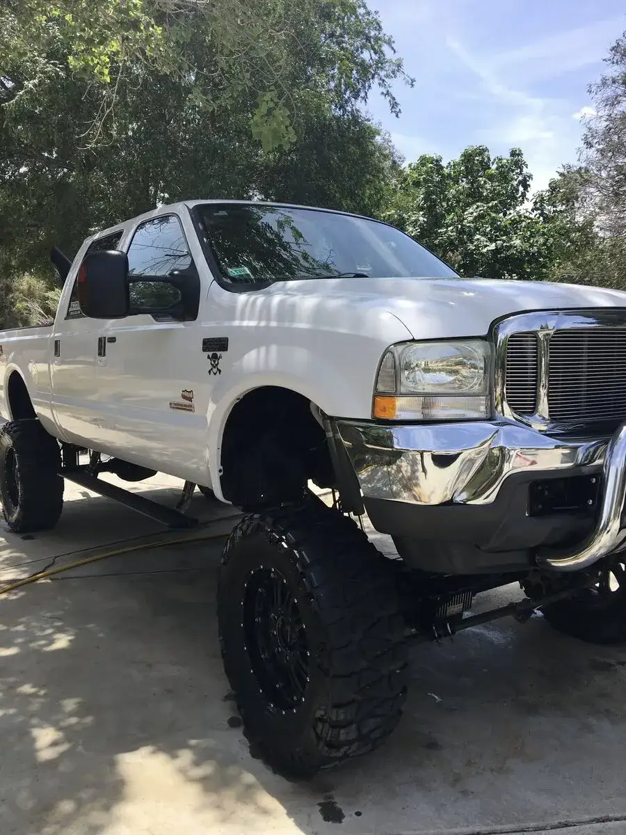 On a city street, Armando King Mobile Detailing performs mobile car detailing for a white truck.