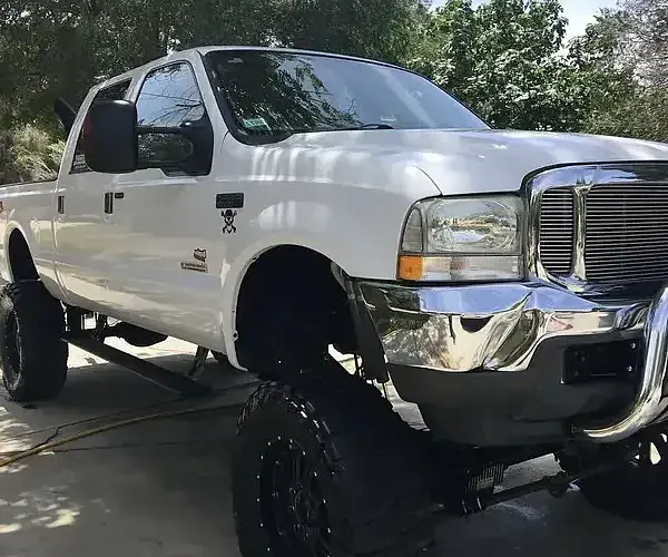 On a city street, Armando King Mobile Detailing performs mobile car detailing for a white truck.