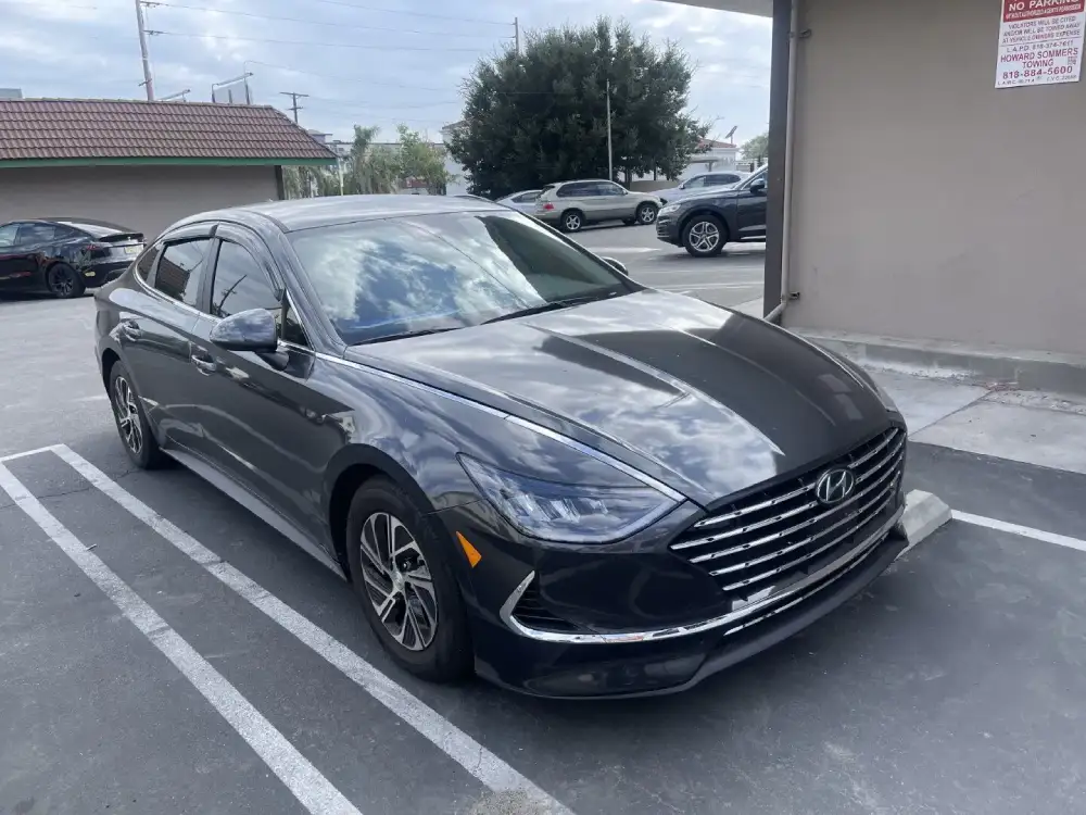 A black car in the parking lot shines after car wash & wax mobile by Armando King Mobile Detailing.
