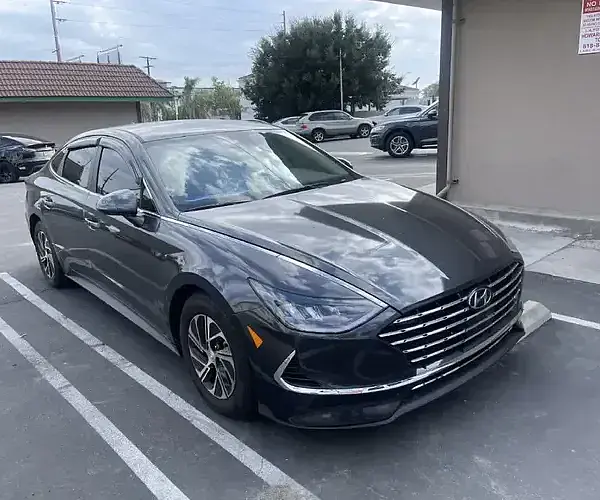 A black car in the parking lot shines after car wash & wax mobile by Armando King Mobile Detailing.